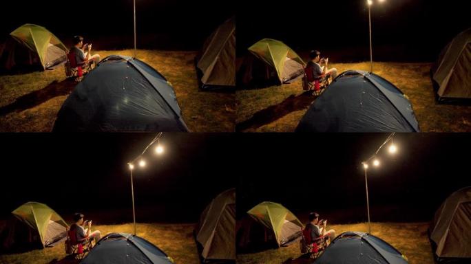 亚洲男孩在帐篷前玩手机游戏，与家人露营，生活方式理念。