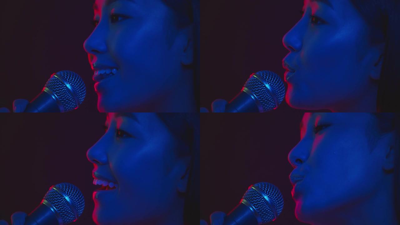 职业歌手。年轻受启发的亚洲妇女的肖像在紫色霓虹灯中唱着美丽的歌曲进入麦克风