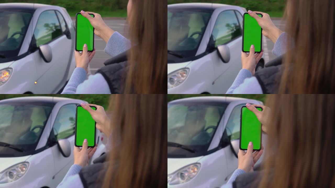 带移动绿屏的女孩在停车场拍照。车祸破碎的镜子
