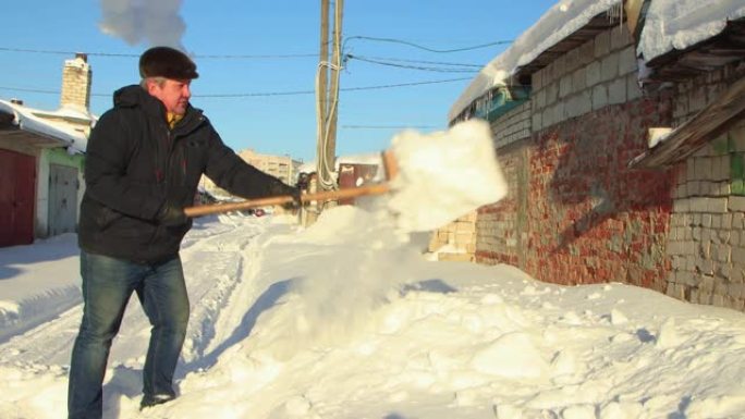 一个穿着暖和衣服的人拿着铲子清除了积雪的道路。
