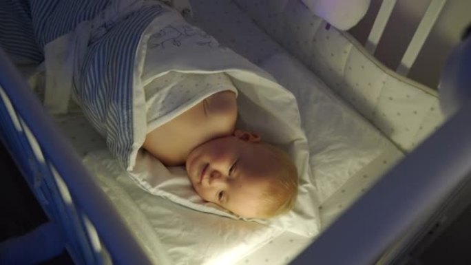 母亲岩石将9个月的男婴包裹在婴儿床中，蹒跚学步的小孩从襁褓中挣脱出来。