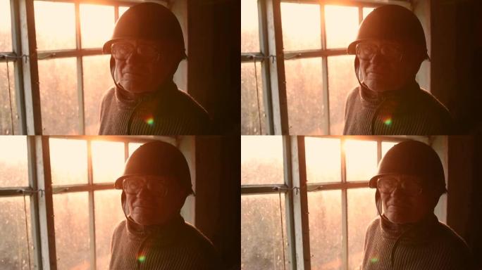 戴眼镜的老人在灰尘中捡起头盔，在房子窗户里戴上头盔