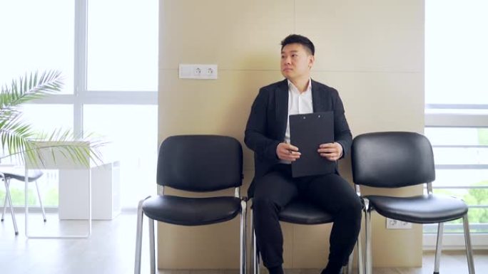 穿着商务正装的亚洲年轻人在候诊室参加结果面试或会议。办公室里的商业男性