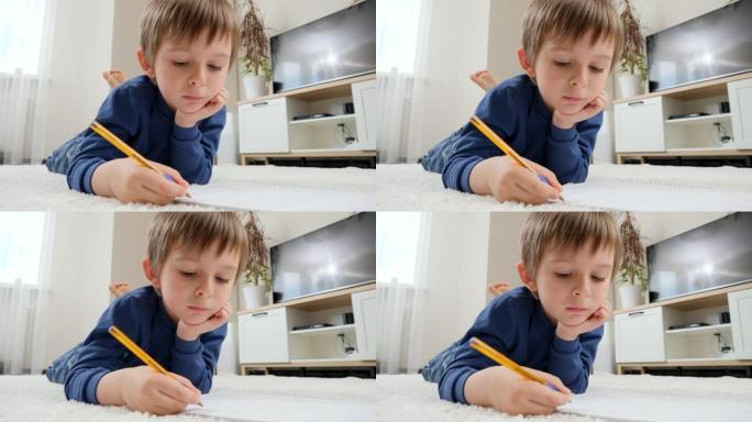 小男孩躺在客厅的地毯上在字帖里做作业。家庭教育和儿童发展的概念。