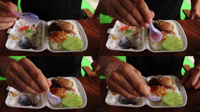 男人吃传统食物，称为Kaw Sach Chrouk，装在聚苯乙烯泡沫塑料容器中