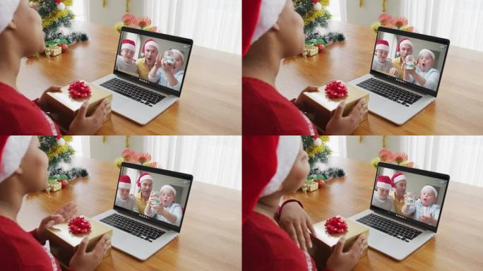 戴着圣诞老人帽子的非洲裔美国妇女使用笔记本电脑与家人在屏幕上进行圣诞节视频通话