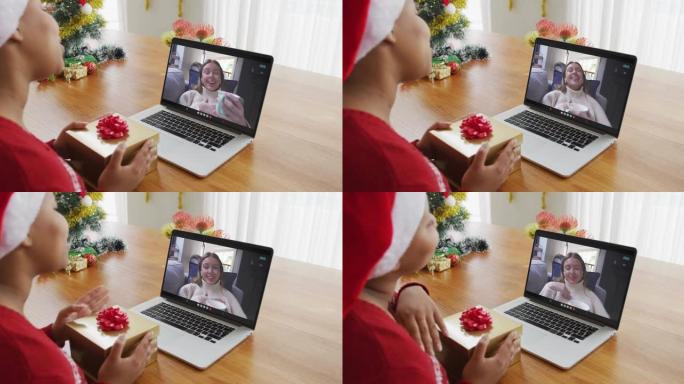 戴着圣诞老人帽子的非洲裔美国妇女使用笔记本电脑进行圣诞视频通话屏幕上的妇女