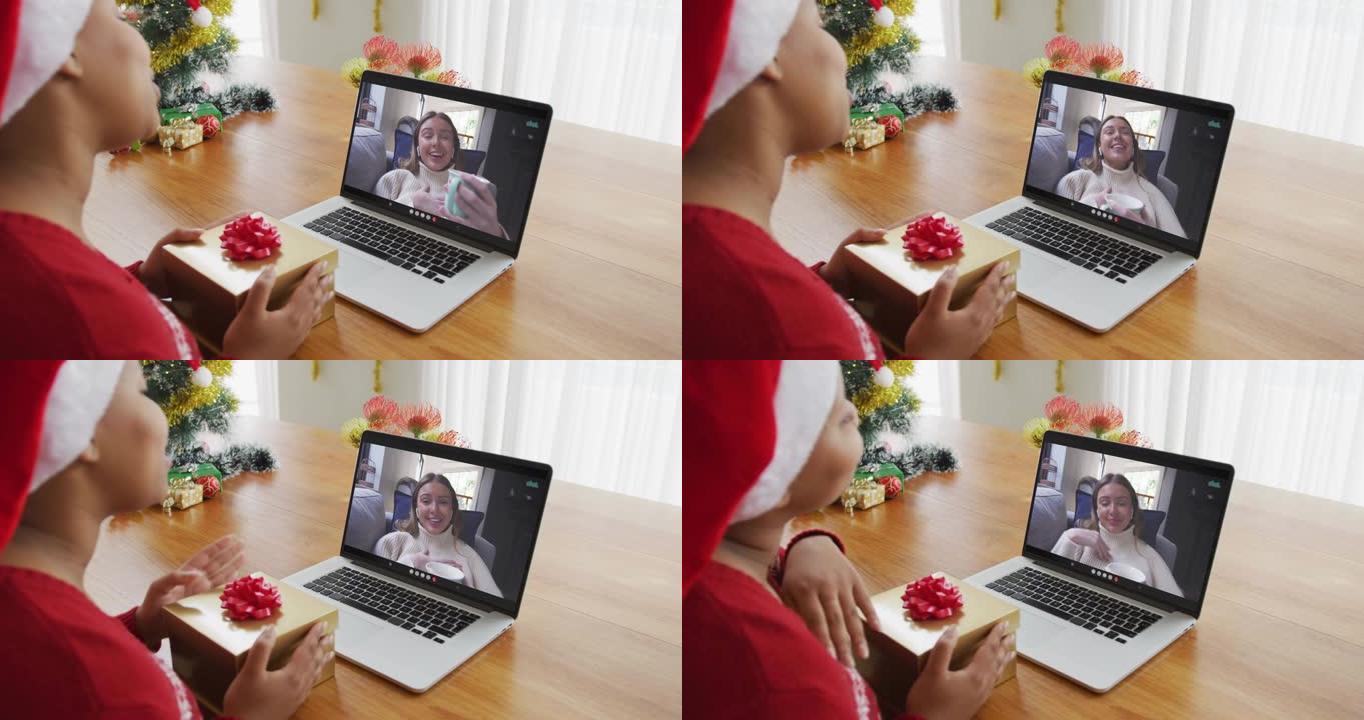 戴着圣诞老人帽子的非洲裔美国妇女使用笔记本电脑进行圣诞视频通话屏幕上的妇女