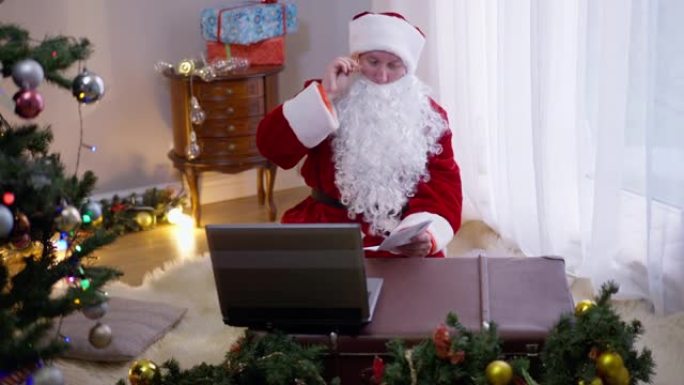 坐在室内客厅的前视图圣诞老人条款签名信封。白种人父亲圣诞节在除夕夜给孩子们写信。假日概念