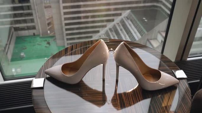 窗户旁边的桌子上有两只女鞋和一枚订婚戒指。