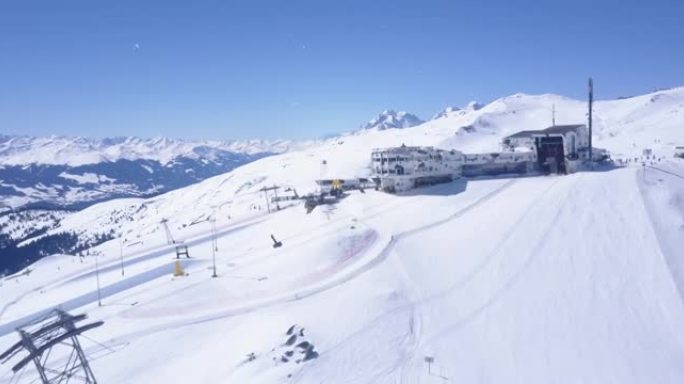 在冬季山区的陡峭滑雪坡上向前飞行。前往带餐厅和酒店的上层缆车站。瑞士Laax