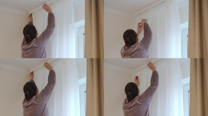 女人靠着窗户，从天花板上悬挂着白色透明的窗帘。窗帘安装在家里。现代家居装修和装饰。