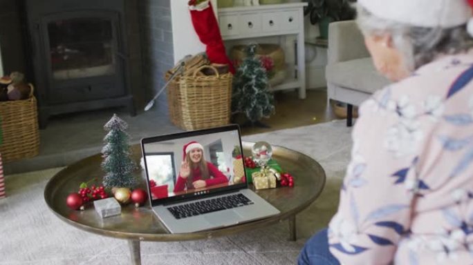 白人高级妇女使用笔记本电脑进行圣诞节视频通话，屏幕上微笑的妇女