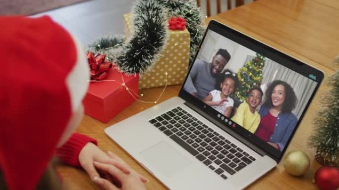 白人妇女在屏幕上与非裔美国人家庭在笔记本电脑上进行圣诞节视频通话