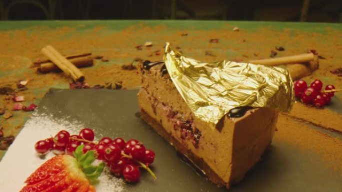 首席炊具把24克拉金片放在布朗尼蛋糕上。美丽昂贵的甜点覆盖着黄金。美味奢华的食物供应方式。漂亮的粉色