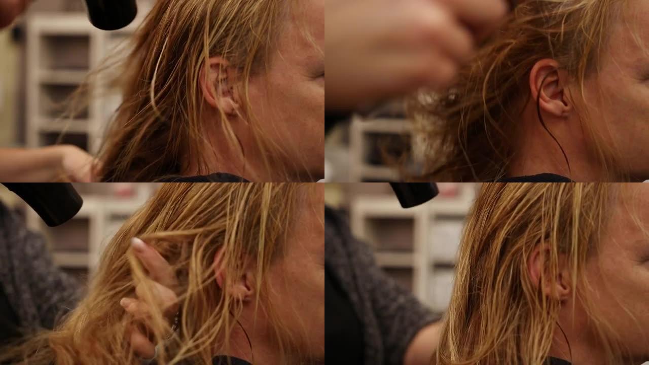 理发师吹干她客户刚洗过的头发。她用手穿过头发以松开头发。