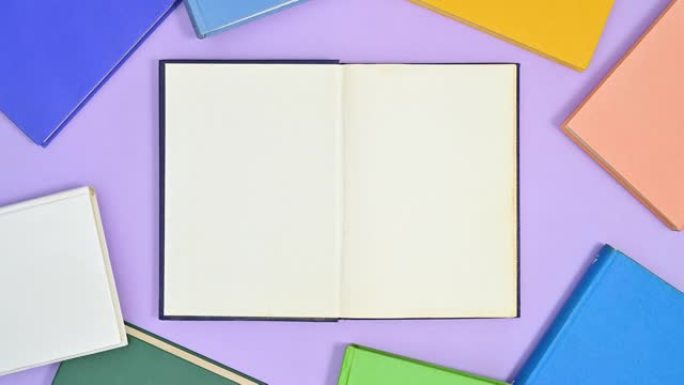深蓝色精装书出现在紫色主题上，打开，鲜艳的色彩书籍出现在制作框架周围。停止运动平铺