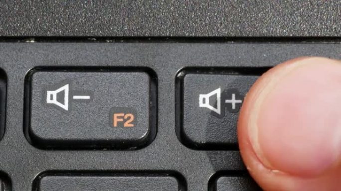 男人在笔记本电脑键盘上调高音量，手指按下计算机键盘上的vol up扬声器键vol按钮，对象宏，细节，