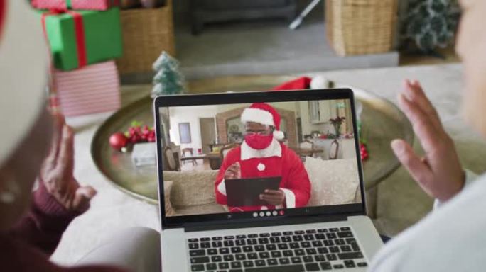 多元化的资深女性朋友使用笔记本电脑与屏幕上的圣诞老人进行圣诞节视频通话