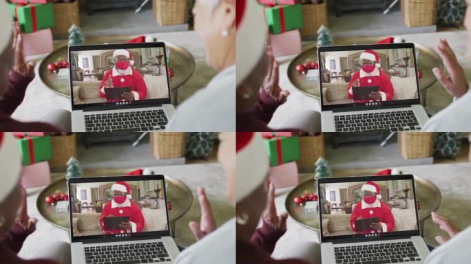 多元化的资深女性朋友使用笔记本电脑与屏幕上的圣诞老人进行圣诞节视频通话
