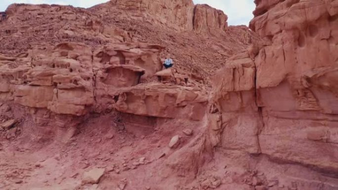 女人在五颜六色的沙漠峡谷和山脉之间的顶部放松瑜伽姿势