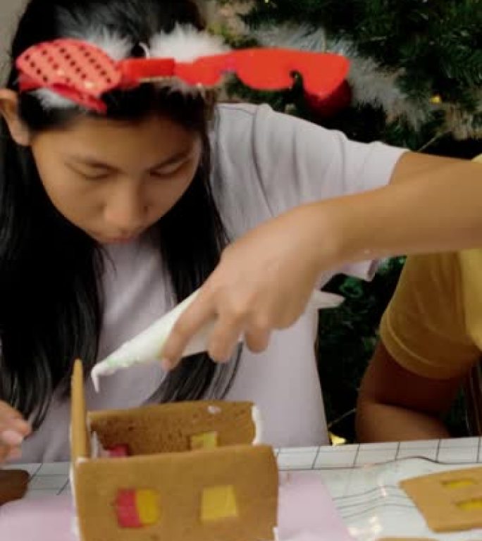 亚洲女孩在晚上在家做姜饼屋，圣诞节庆祝生活方式。