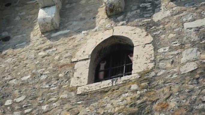 一座古老的石头建筑的禁止窗户，里面有人手