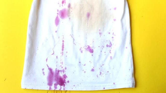 石榴石和饮料白色t恤上的脏渍。石榴籽飞入黄色背景的衬衫中。