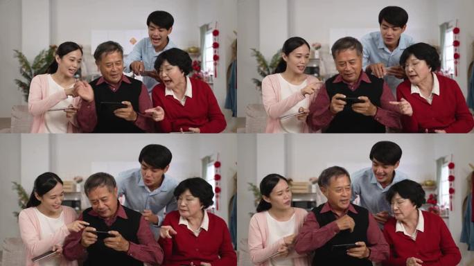 穿着红色衬衫的年迈的父亲在玩手机游戏时挥舞着双手，感到恼火，因为春节期间其他家人在家里指着他唠叨。