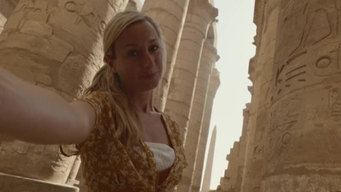 年轻女子在卢克索观光古埃及神庙采取很酷的自拍照。
