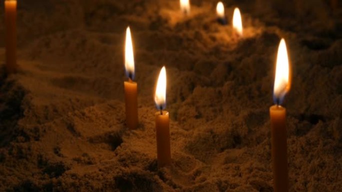 细长的黄色教堂蜡烛在沙子中燃烧