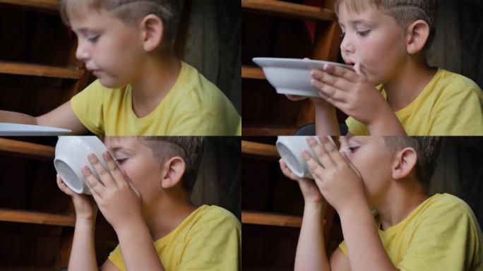 肖像。一个穿黄色衬衫的十几岁男孩吃汤。他在碗的边缘吃完食物。健康自制食品概念