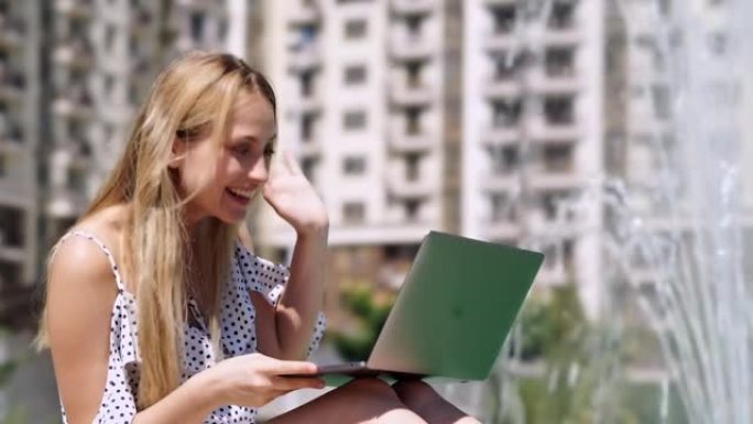 穿着裙子的开朗金发女人在笔记本电脑上通过视频通话