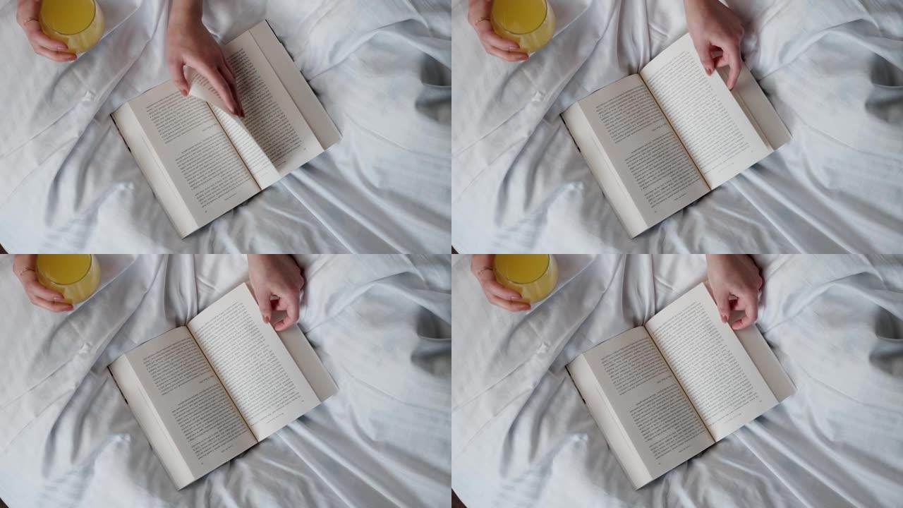女人在白色床上喝天然果汁用手翻书