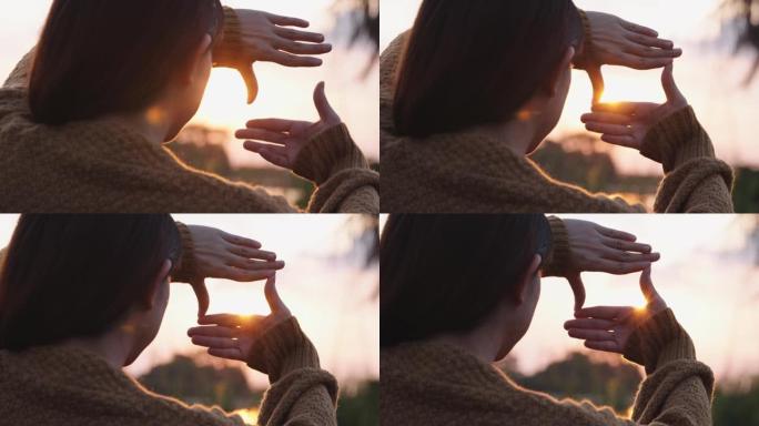 新年计划和视觉概念，女人的手与日落做框架手势，女性捕捉日出。