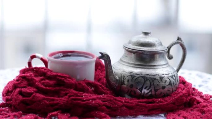 将华丽的金属茶壶中的热气腾腾的热茶倒入户外雪下的杯子中