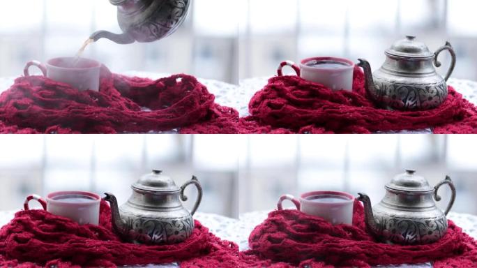 将华丽的金属茶壶中的热气腾腾的热茶倒入户外雪下的杯子中