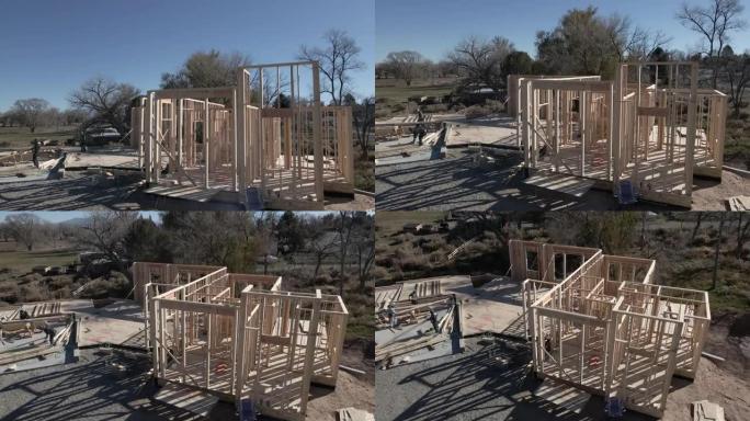随着三个木匠努力将墙壁钉在一起以抬高建筑物的框架施工阶段，房屋的向下倾斜无人机上升