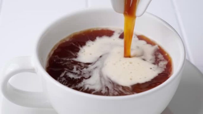 热黑咖啡倒入白色瓷砖厨房背景的杯子中。