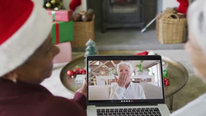 多元化的资深女性朋友使用笔记本电脑与屏幕上的幸福女人进行圣诞节视频通话