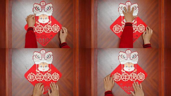 男子将农历新年的老虎2022吉祥物贴在门上没有徽标没有商标翻译的中文是新年快乐
