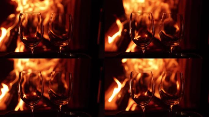 两杯酒的背景是壁炉里燃烧的火。两个空酒杯，带舒适温暖的壁炉，背景上有火焰。