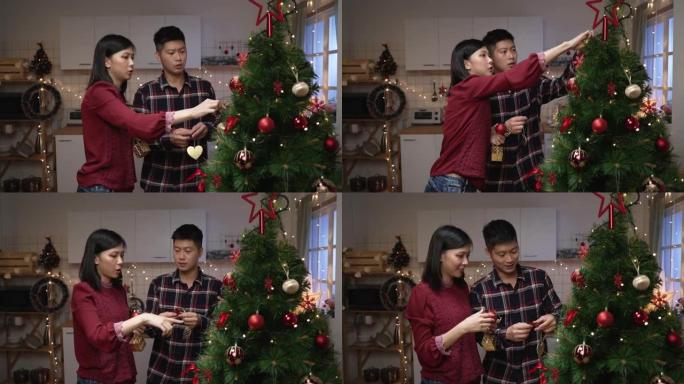 快乐的日本亚洲夫妻一起工作，用挂饰装饰圣诞树，同时为即将到来的寒假在家做准备