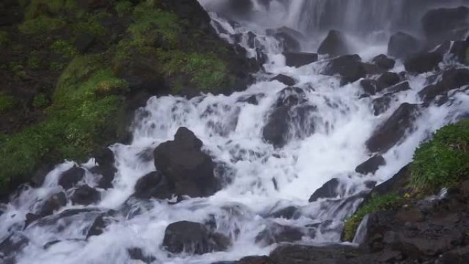 美丽的风景，一条快速的山河在岩石石块之间流动。瀑布从山顶落下。山坡上的雪和冰川。高加索山脉，靠近埃尔