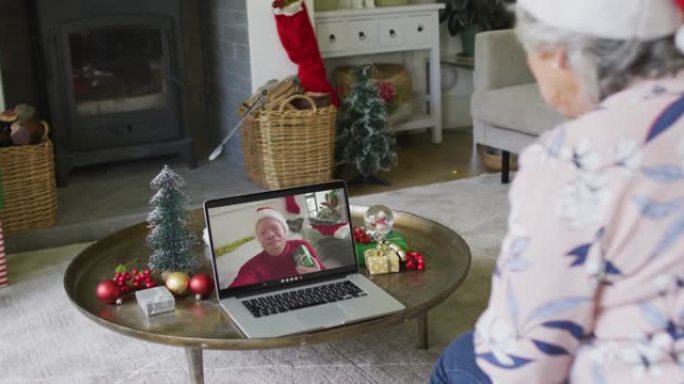 白人高级妇女使用笔记本电脑进行圣诞节视频通话，屏幕上微笑的男人