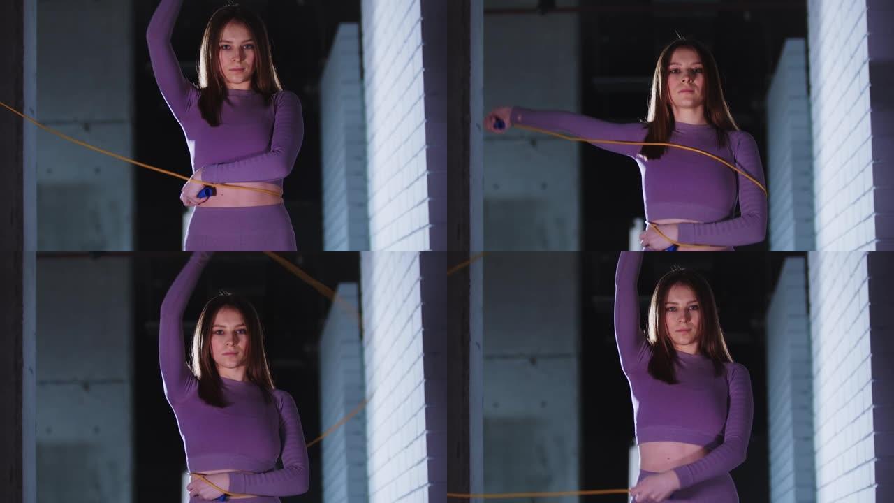 穿着紫色运动服的年轻美女玩着跳绳，看着镜头