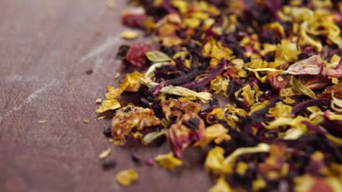 草药花茶的干叶和花瓣，配以果片和芙蓉。散落在一张质朴的木桌上