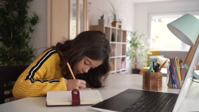 可爱的白人小学女学生做她的家庭作业，同时使用了大量的技术