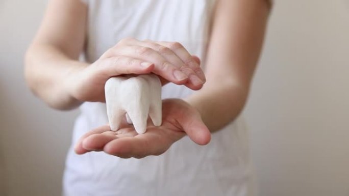 健康牙科保健概念。女人手握白色健康牙齿模型孤立在白色背景上。牙齿美白，口腔卫生，牙齿修复，牙医日
