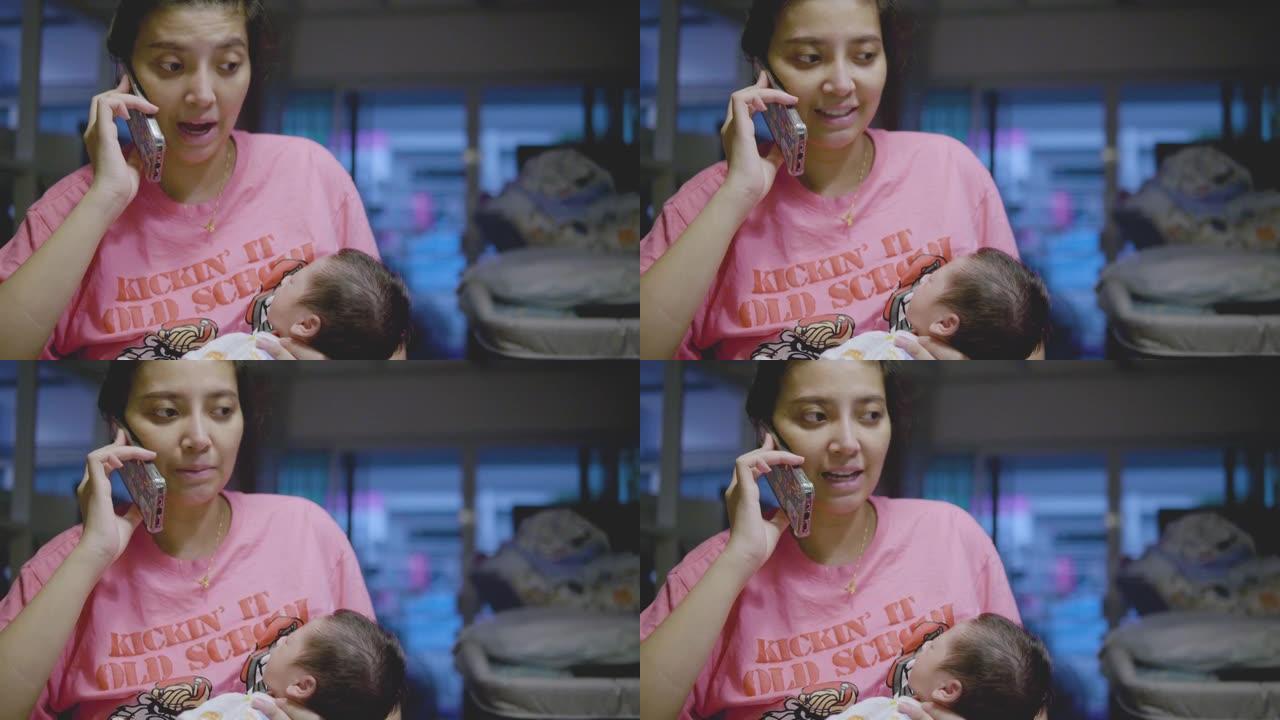 亚洲妈妈在电话上工作，抱着正在睡觉的男婴。